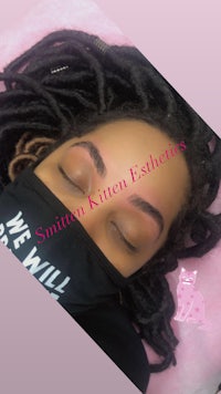 a woman with dreadlocks sleeping on a pink pillow